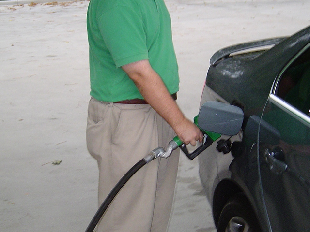 A person pumping gas into a passenger car