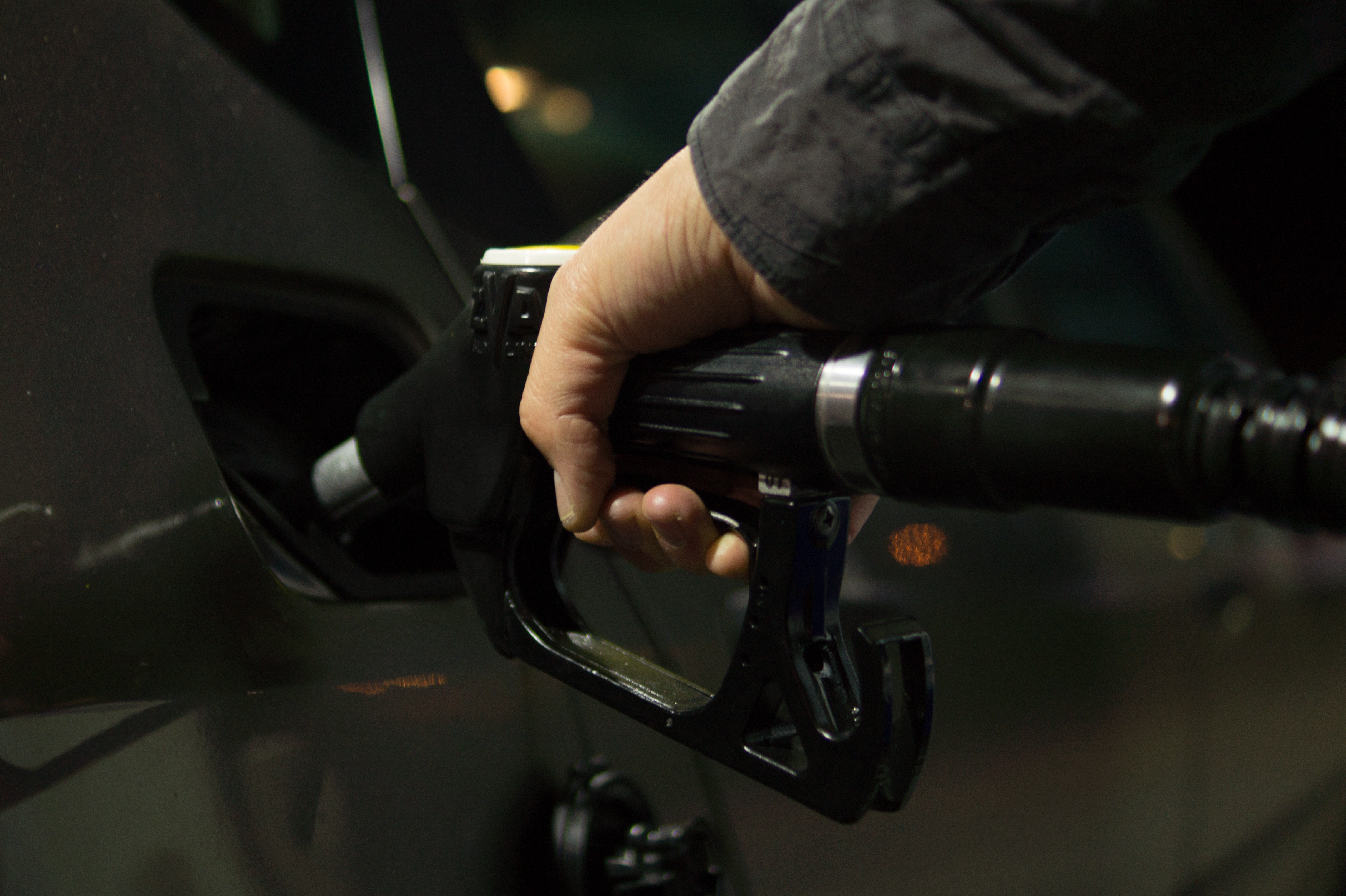 A driver refueling a passenger car at a gas station at night